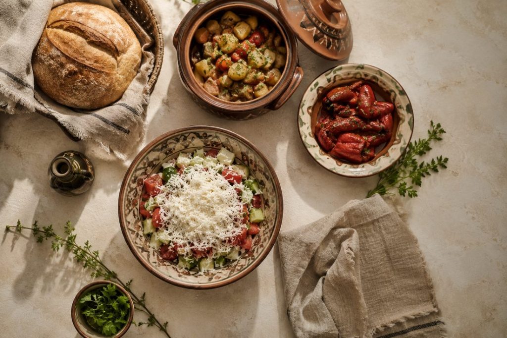 A traditional Bulgarian table with shopska salad, slow-cooked vegetables and bread